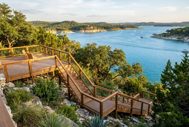 A raised wood deck and long stair run stepping down a rocky Texas hillside above a lake